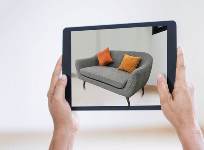 Nach oben gehaltenes Tablet mit Sofabild steht für Social-Media-Marketing im einrichtenden Handel