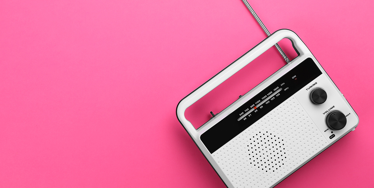 Ein Radio liegt auf einem pinken Hintergrund. Radiokampagne effektiv planen.