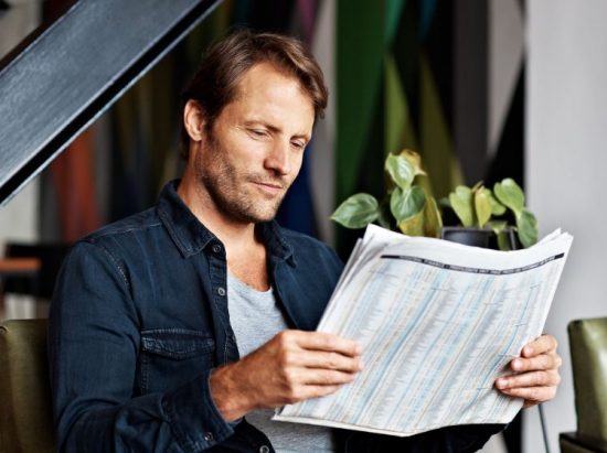 Mann liest Zeitung aus Printbereich