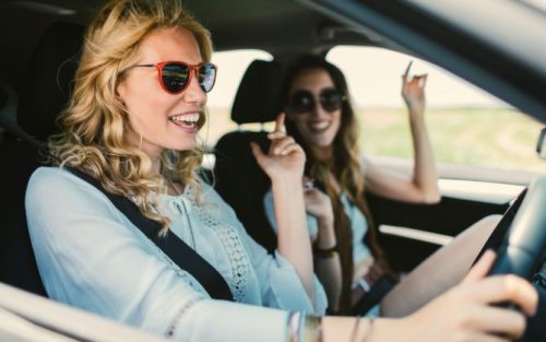 Lachende junge Frauen im Auto mit Sonnenbrillen steht für Radio Portfolio