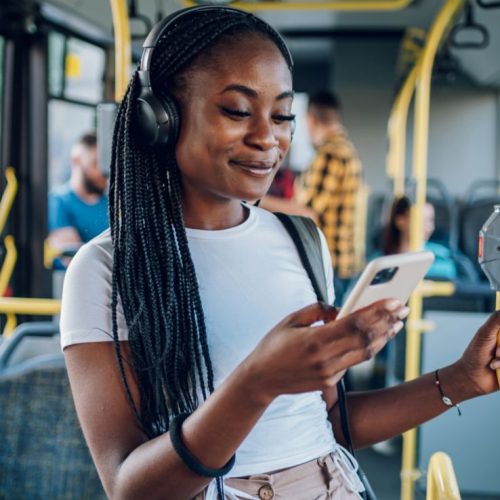 Junge Frau in Bus mit Kopfhörern und Smartphone symbolisiert Radio