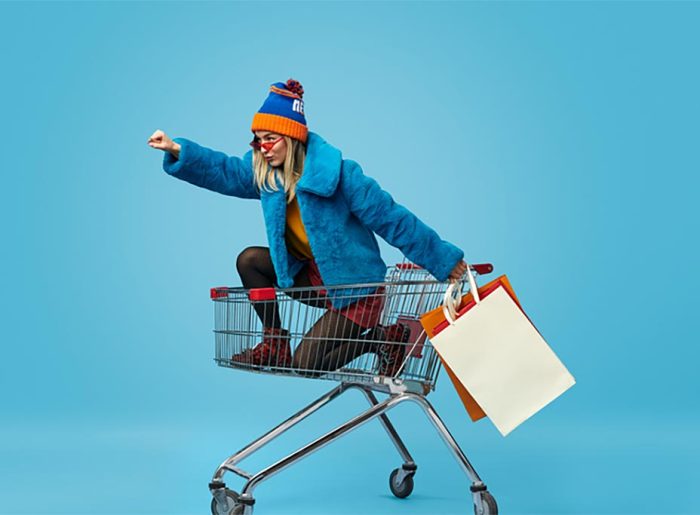 Frau im Einkaufswagen mit Einkaufstaschen symbolisiert wirkungsvolle Verkaufsförderung