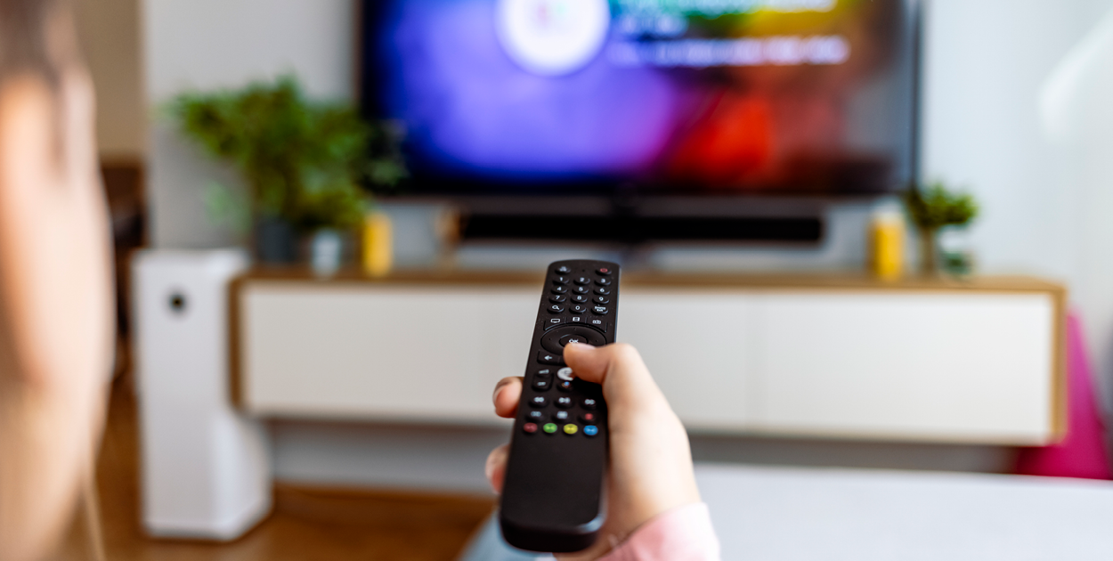 Fernbedienung vor Fernseher symbolisiert Addressable TV und regionale Fernsehwerbung
