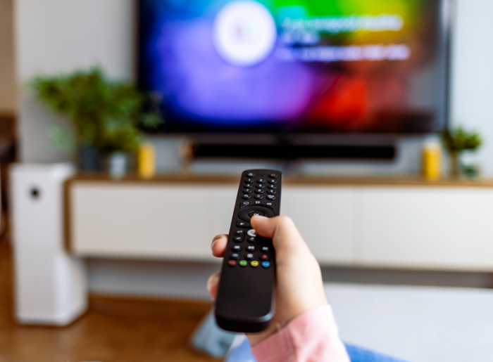 Fernbedienung vor Fernseher symbolisiert Addressable TV und regionale Fernsehwerbung