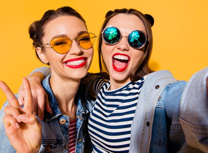 Zwei junge Frauen mit Sonnenbrille, die ein Selfie machen, symbolisieren Aufmerksamkeitsspanne und Social Media