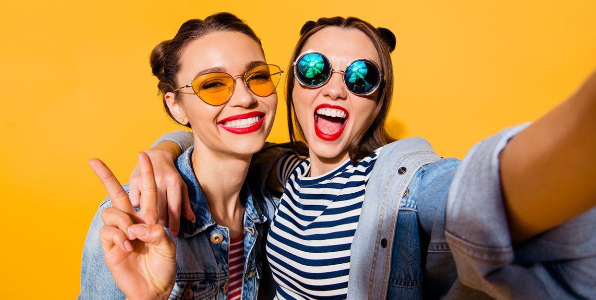 Zwei junge Frauen mit Sonnenbrille, die ein Selfie machen, symbolisieren Aufmerksamkeitsspanne und Social Media