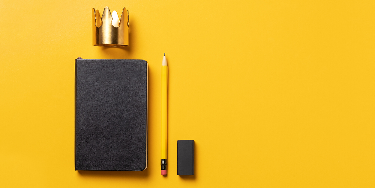 Notizbuch, Stift, Radiergummi und Krone stehen für Tipps zur erfolgreichen Jahresplanung für Unternehmen