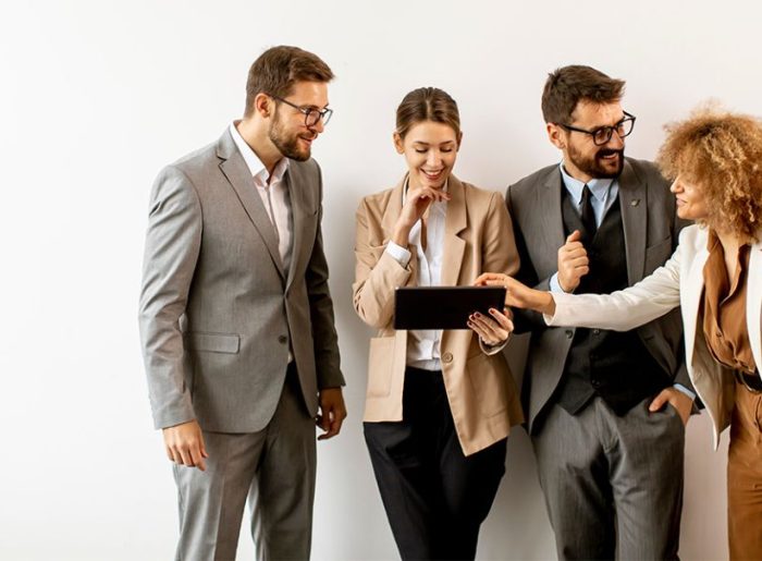 4 Geschäftsleute in einer Reihe mit Tablet, die sich unterhalten, symbolisieren Mitarbeiter-Kommunikation