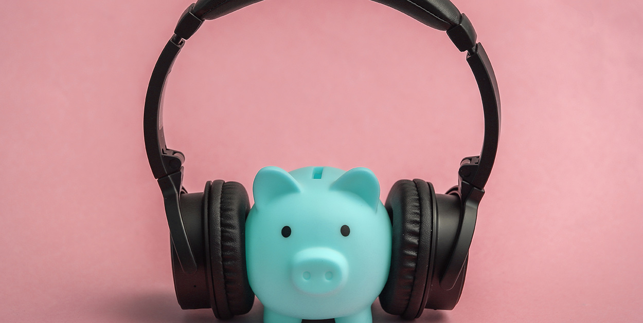 Sparschwein mit aufgesetzten Kopfhörern symbolisiert Kosten von Radiowerbung