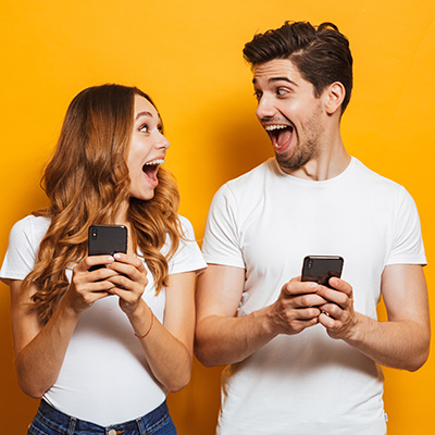 Überraschte Mann und Frau mit Handy in der Hand symbolisieren Recruiting-Video.