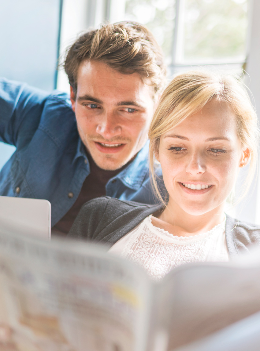 Frau und Mann lesen die Tageszeitung und symbolisieren erfolgreiche Anzeigenschaltung.