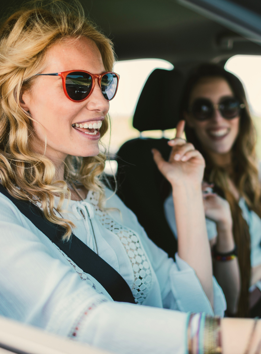 Frauen im Auto sind glücklich und hören Radiowerbung