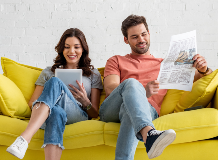 Mann und Frau auf der Couch mit Zeitung und IPad symbolisieren Werbung in Anzeigenblättern.